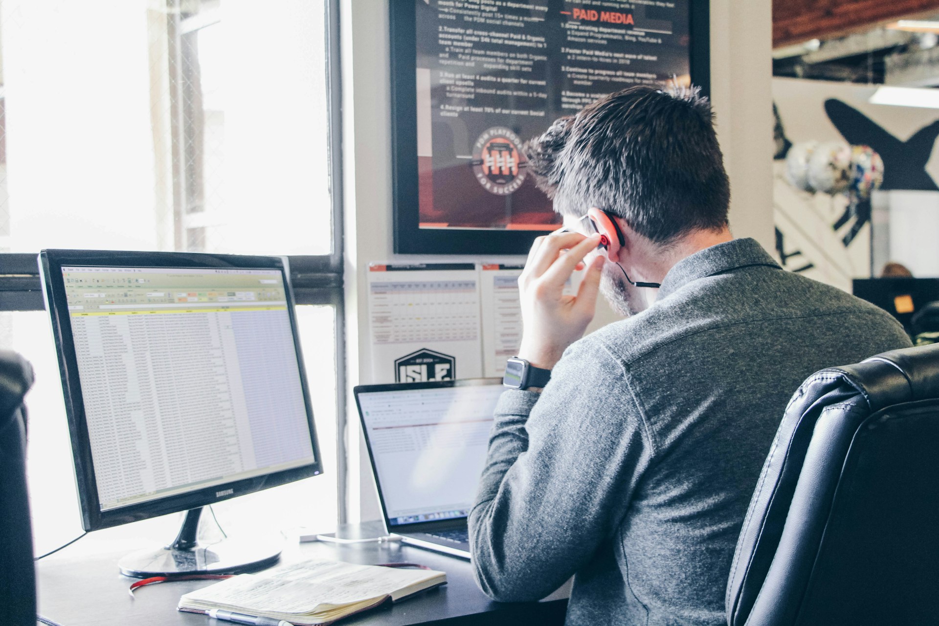 A chamber member at his desk with two monitors, taking a phone call.
